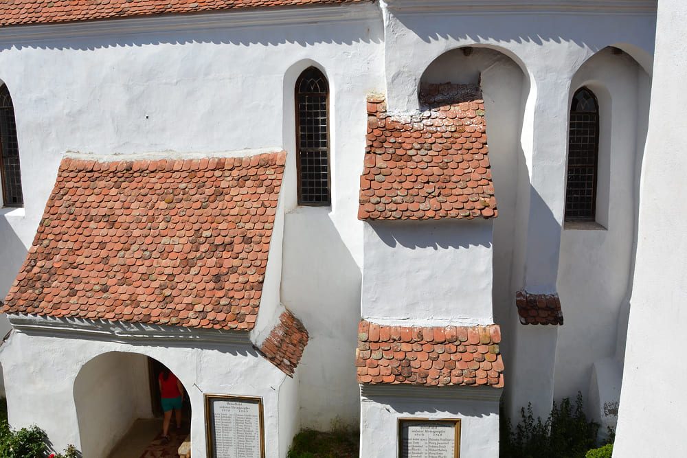 Layered terracotta tile roofs and stark white lime-washed walls at the UNESCO-listed Viscri fortified church in Transylvania.