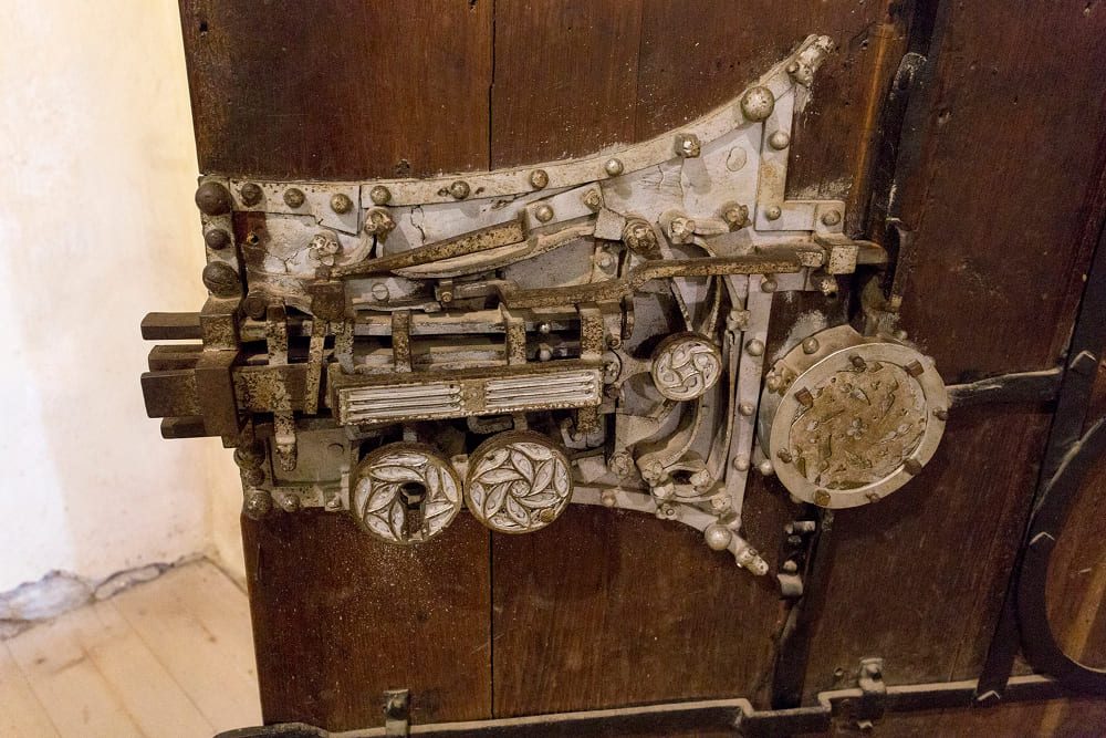 Close-up of an antique metal locking mechanism embedded in a rustic wooden door