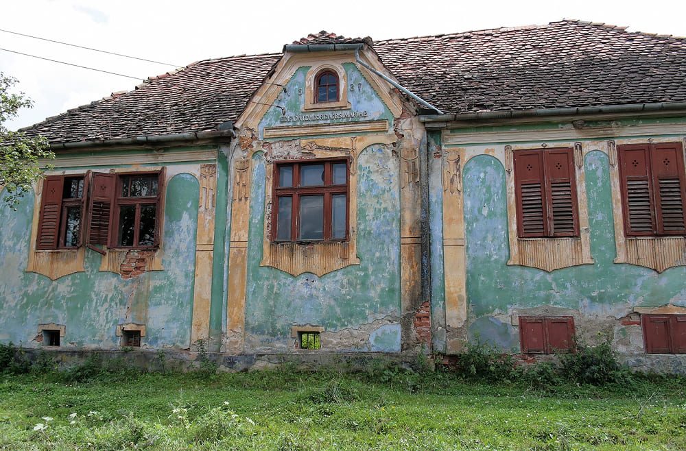 Historic village home in Viscri showing authentic architectural details, wooden window shutters, and the region's famous 'Viscri blue' lime wash.